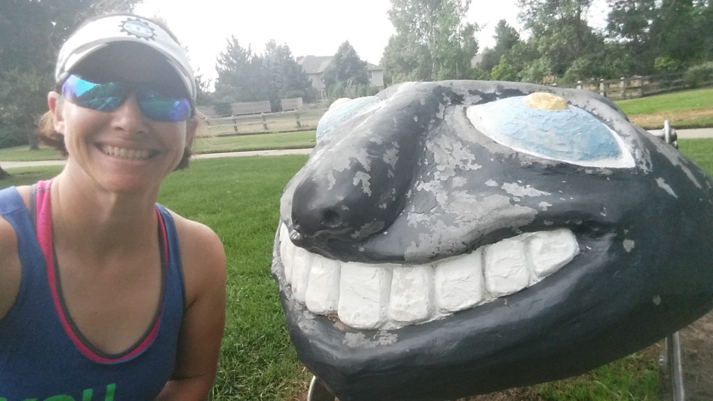 Coach Nicole taking a quick break to take a picture with some park art during her first run since elbow surgery.