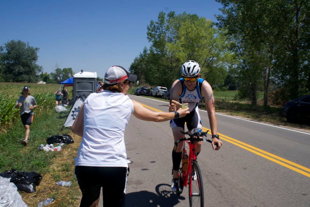 Coach Nicole handing out a snow cone to an IRONMAN Boulder athlete at the Infinite - 303Triathlon snow cone station on August 7, 2016.