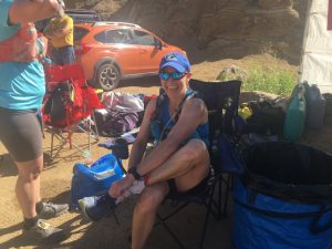 Nicole sitting in a chair at Aid Station #2 in North Cheyenne Canyon park at the Pikes Peak Ultra. She needed to adjust her shoes to fit better for the remainder of the race.