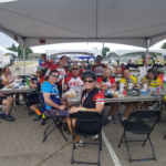 TeamNEO-lunch Cyclists sitting at tables under an event tent having lunch