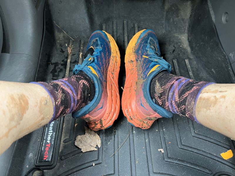 bright colored Hoka trail shoes covered in mud