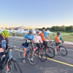 IMG_6272 five cyclists lined up on a road getting ready to ride at sunrise