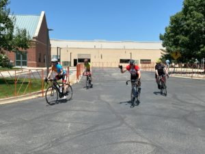 four cyclists riding towards a finish in a parking lot